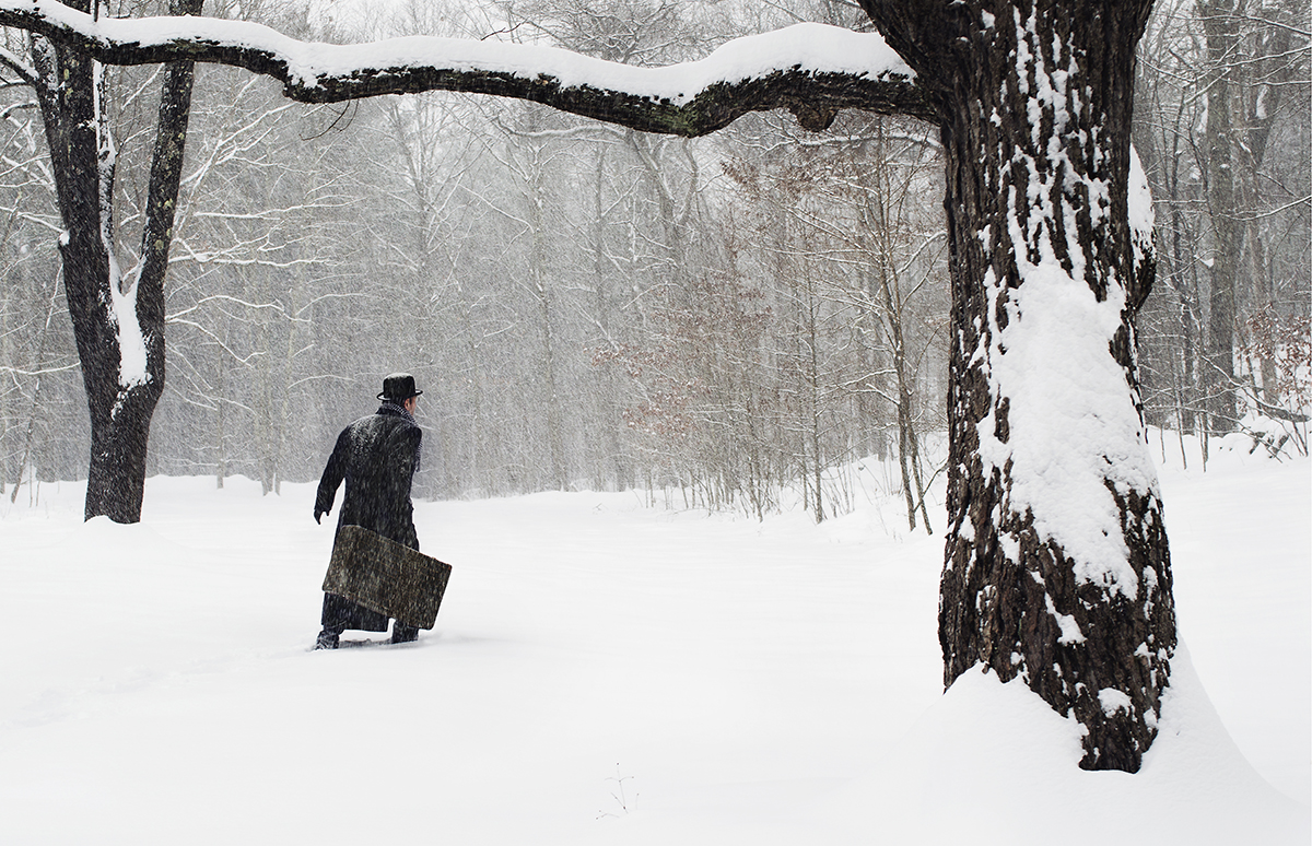 man with suitcase walking in snow