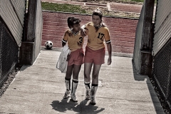 girl helping injured teammate off soccer field